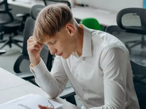 a man sitting at a desk with his hand on his head